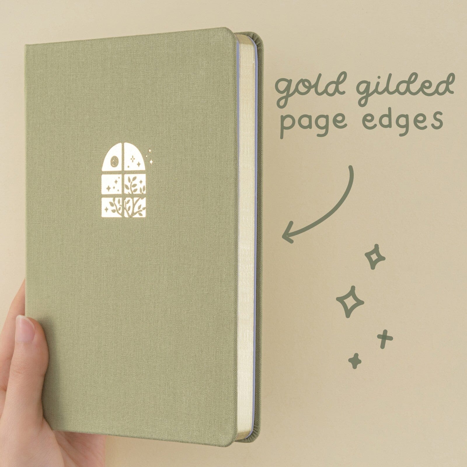 Close up of Komorebi bullet journal with green velvet cover and gold foil illustration of a window with the sun and plants
