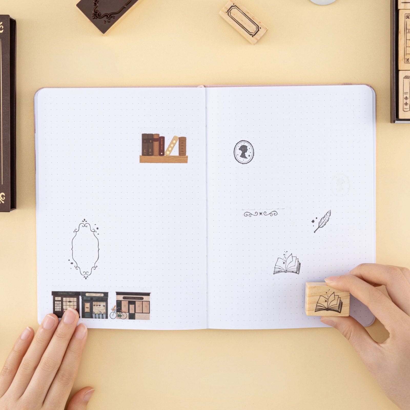  Hand holding opened book stamp and stamping on bullet journal