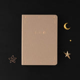 Tsuki Stardust Dawn Bullet Journal with rose gold details and powdered lilac linen on black background 