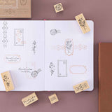 Tsuki ‘Vintage Rose’ Bullet Journal Stamp Set with vintage aesthetic on open Tsuki ‘Vintage Rose’ Limited Edition Bullet Journal on mauve background