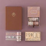 Tsuki ‘Vintage Rose’ Bullet Journal Stamp Set with Tsuki ‘Vintage Rose’ Washi Tapes on Tsuki ‘Vintage Rose’ Limited Edition Bullet Journal with burnt paper on mauve background