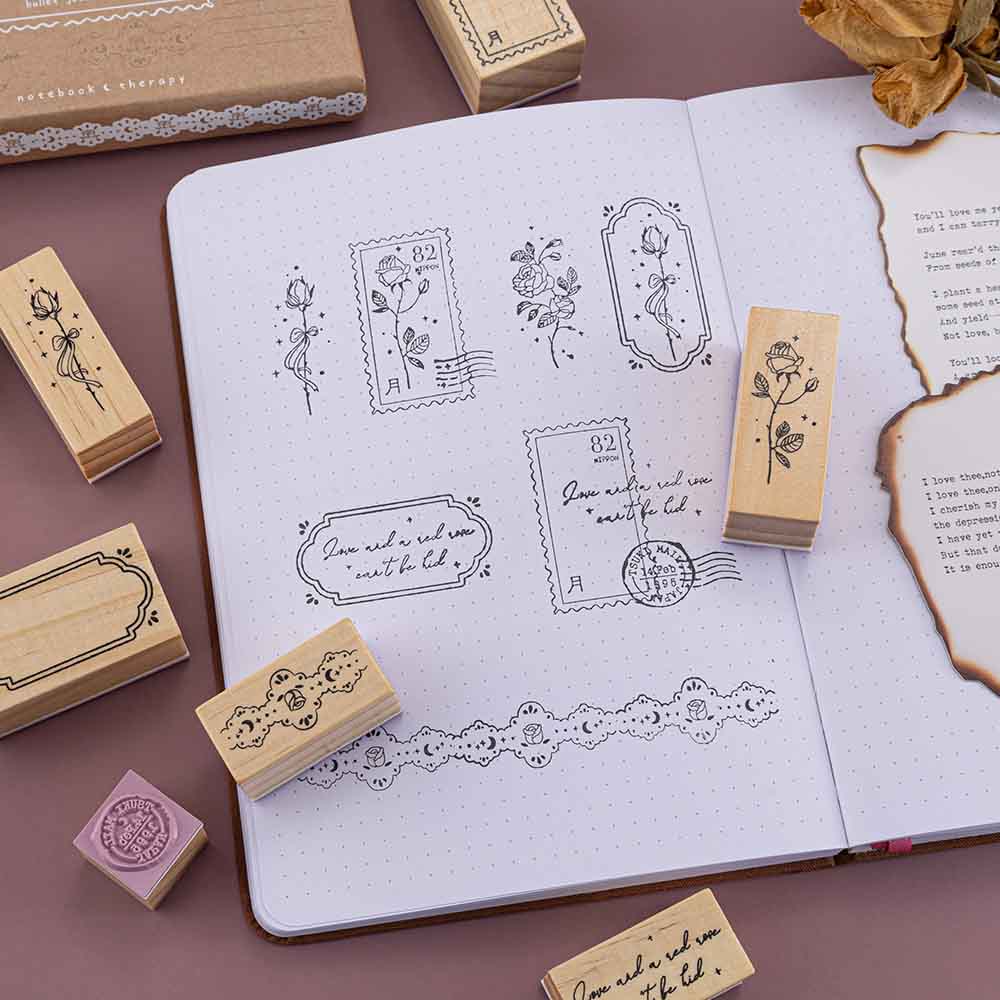 Tsuki ‘Vintage Rose’ Bullet Journal Stamp Set with vintage aesthetic on open Tsuki ‘Vintage Rose’ Limited Edition Bullet Journal with burnt paper and dried roses on mauve background
