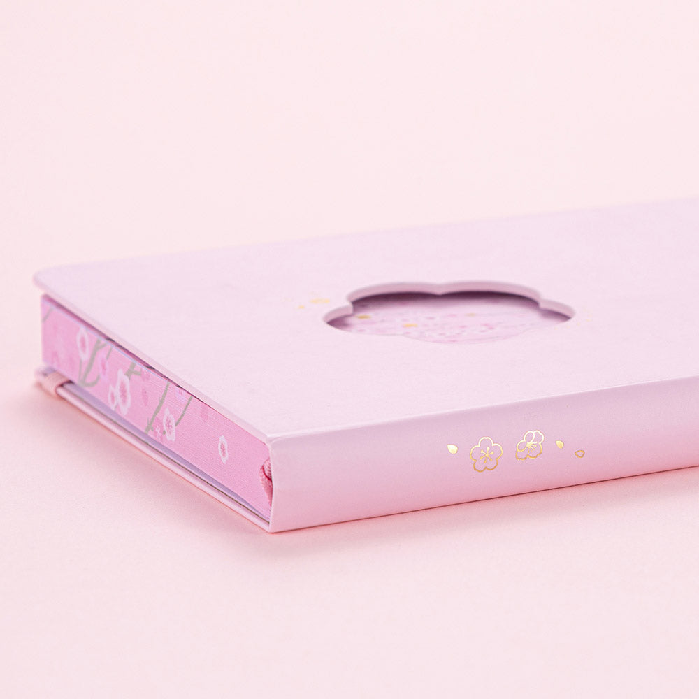 Close up of open Tsuki Four Seasons: Spring Collector’s Edition 2022 Bullet Journal with two bookmark ribbons on light pink background