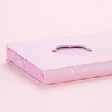 Close up of open Tsuki Four Seasons: Spring Collector’s Edition 2022 Bullet Journal with two bookmark ribbons on light pink background