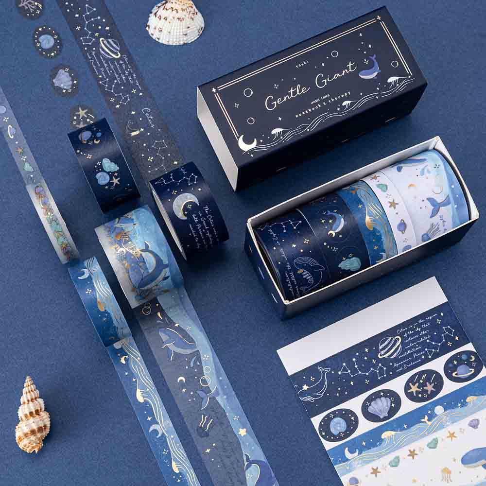 Box of Gentle Giant washi tape + the rolls of washi laid out against a blue background