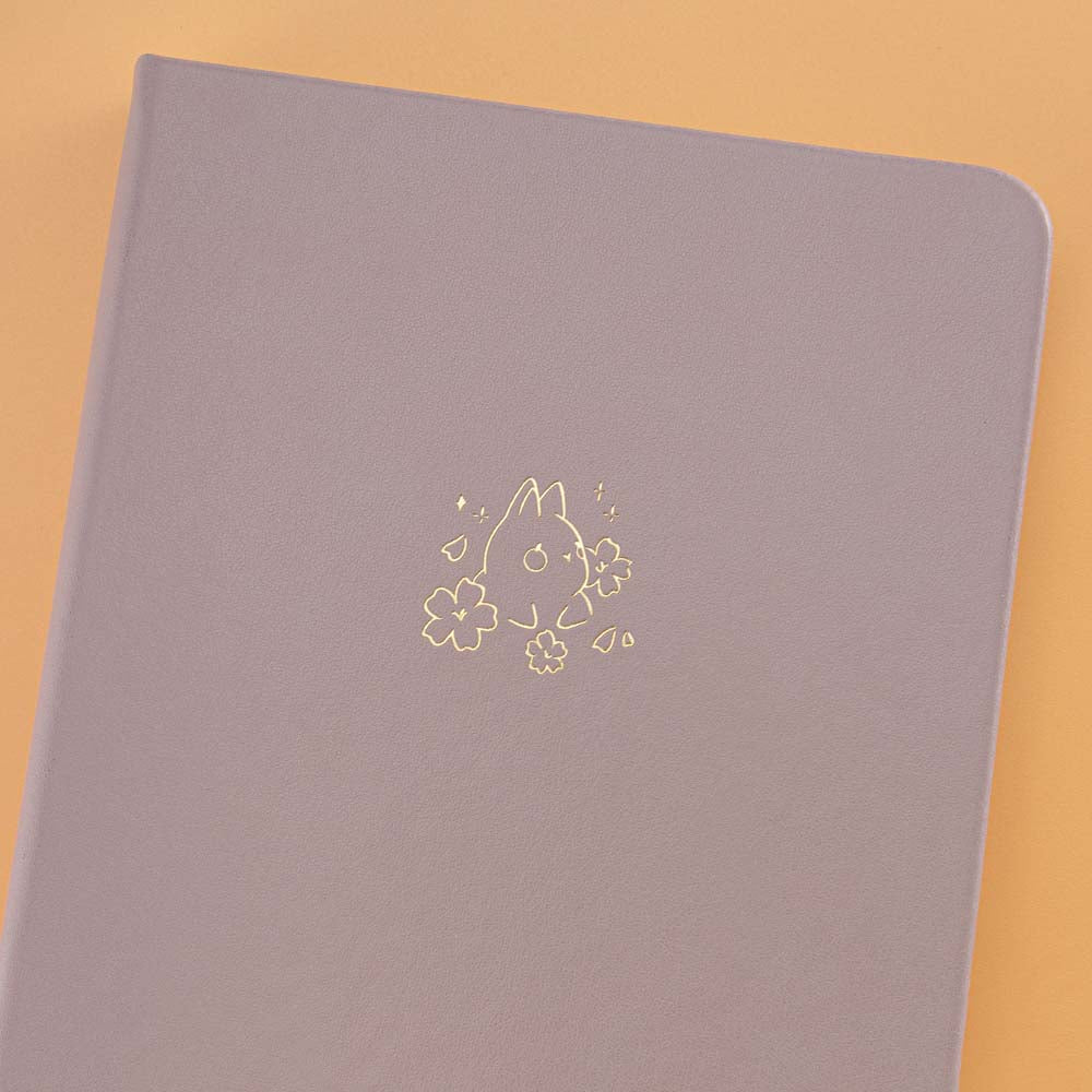 Close up of open front page of Tsuki Blush Pink ‘Bunny Blush’ Limited Edition Bullet Journal designed with Blossom Bujo on apricot background