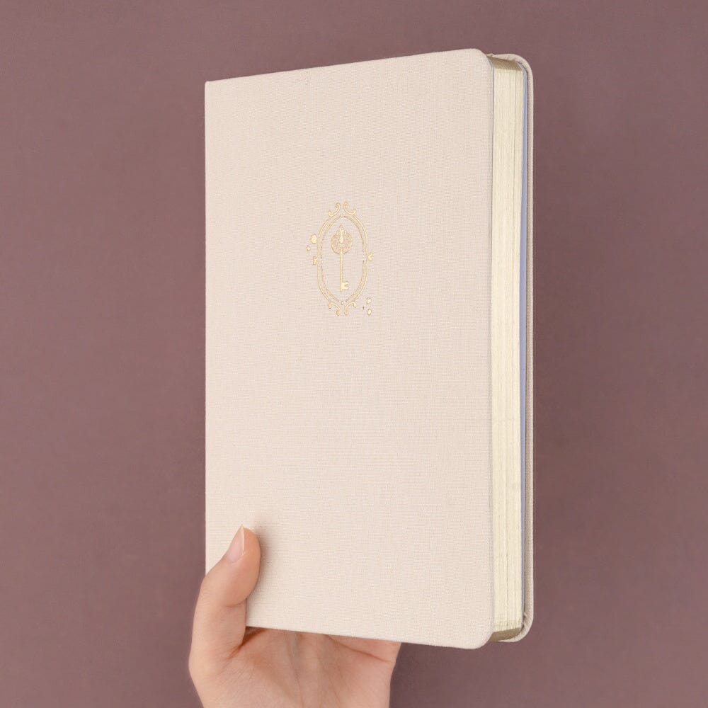 Hand holding up Love Lock bullet journaal notebook showing gold page edgess