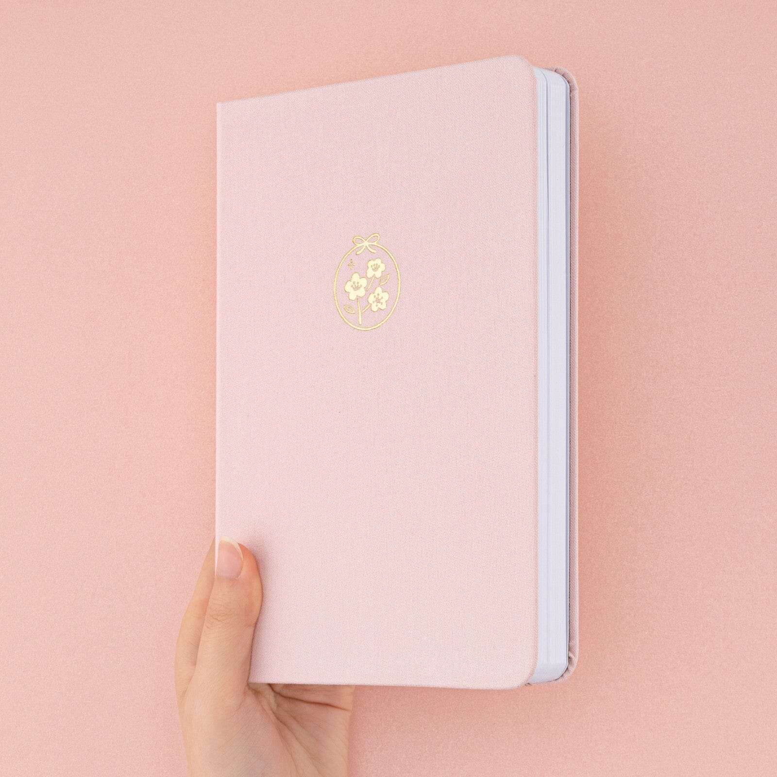 Hand holding Tsuki Sakura Breeze limited edition bullet journal by Notebook Therapy at an angle