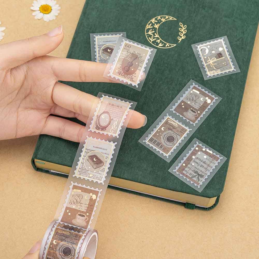 Hand stretching out Tsuki Light Academia PET stamp tape roll on green velvet bullet journal