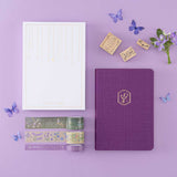 Tsuki ‘Enchanted Garden’ lavender foil design on purple linen bullet journal on purple background 