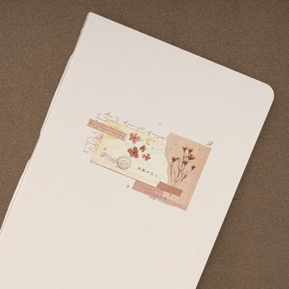 Vintage style collage with dried flowers and ripped paper printed on textured paper cover of a junk journal notebook