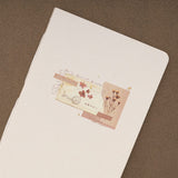 Vintage style collage with dried flowers and ripped paper printed on textured paper cover of a junk journal notebook