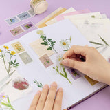 Hand sicking a daisy flower sticker on a bullet journal with flower stickers all over the page