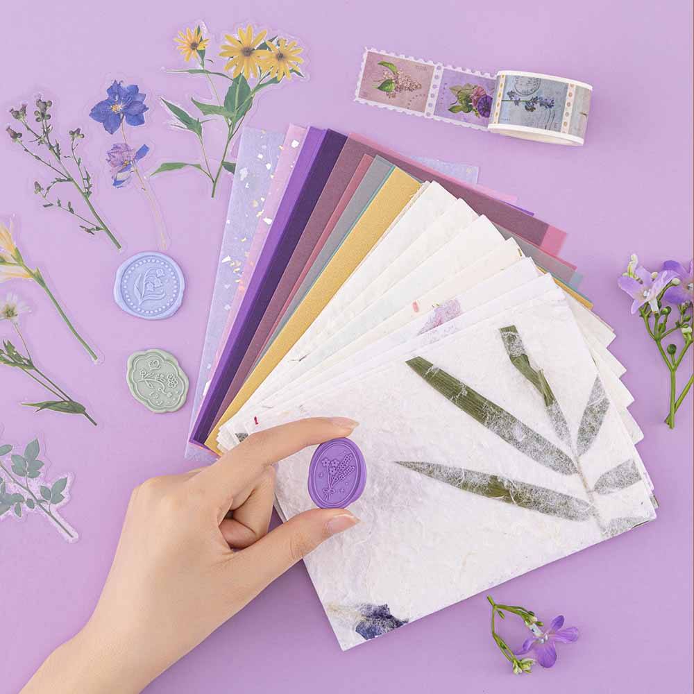 Hand holding a lavender wax seal stamp over the sheets of textured paper