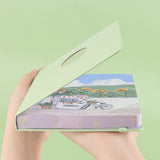 Angled photo of Tsuki Four Seasons Summer Collectors Edition 2022 sage bullet journal notebook showing the illustrated page edges