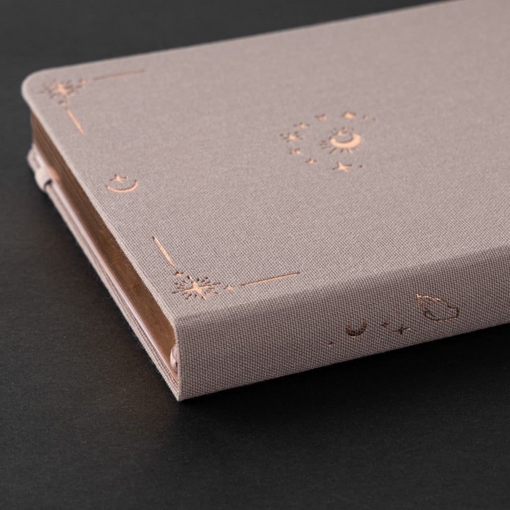 Close up of Tsuki Moonlit Dusk Bullet Journal lilac linen cover with rose gold design with crescent moon and stars around it