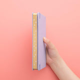 Tsuki ‘Full Bloom’ Limited Edition Bullet Journal held in hands at spine angle in coral pink background