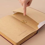Open back page pocket of Tsuki Kraft Paper Limited Edition Bullet Journal in Kinoko with free bookmark gift held in hand on beige background
