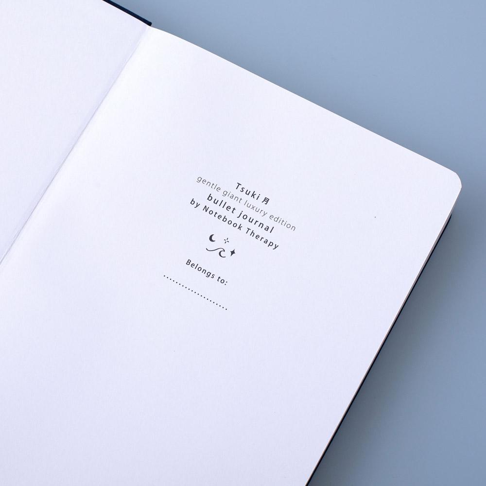 Close up of deep blue textured vegan leather Tsuki Gentle Giant luxury edition bullet journal on open front page on blue background
