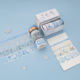 Flatlay of Winter Moonflower washi tapes with opened box and 5 washi tapes unrolled on blue background