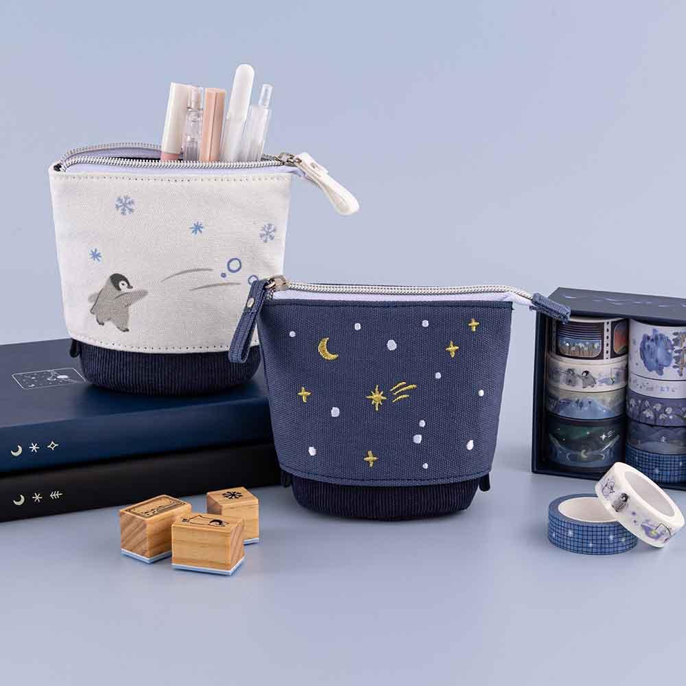 Tsuki ‘Dreams of Snow’ Pop-Up Pencil Cases in Starry Night and Playful Penguin on Tsuki ‘Winter Wishes’ Limited Edition Bullet Journal and Tsuki ‘Winter Journey’ Limited Edition Bullet Journal and with Tsuki ‘Dreams of Snow’ Bullet Journal Stamps with Tsuki ‘Dreams of Snow’ Holographic Washi Tape Set in light blue background