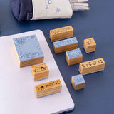 Close up of Tsuki ‘Dreams of Snow’ Bullet Journal Stamp Set on open bullet journal spread with Tsuki ‘Dreams of Snow’ Pop-Up Pencil Case in Starry Night on navy background