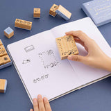 Tsuki ‘Dreams of Snow’ Bullet Journal Stamp Set held in hands over open bullet journal spread on navy background