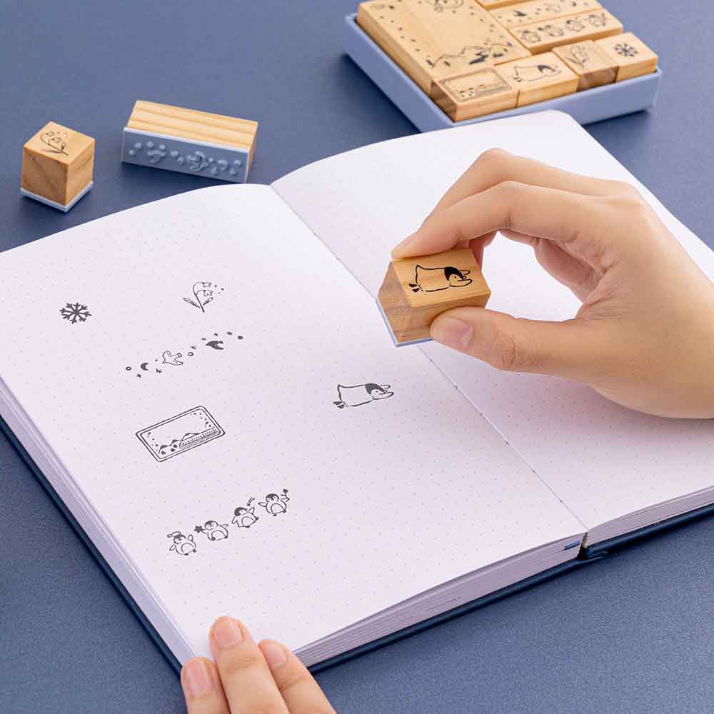 Tsuki ‘Dreams of Snow’ Bullet Journal Stamp Set held in hands over open bullet journal spread in navy background