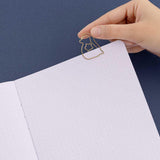 Close up of open page of Tsuki ‘Winter Wishes’ Limited Edition Bullet Journal with free paperclip gift held in hand on navy background