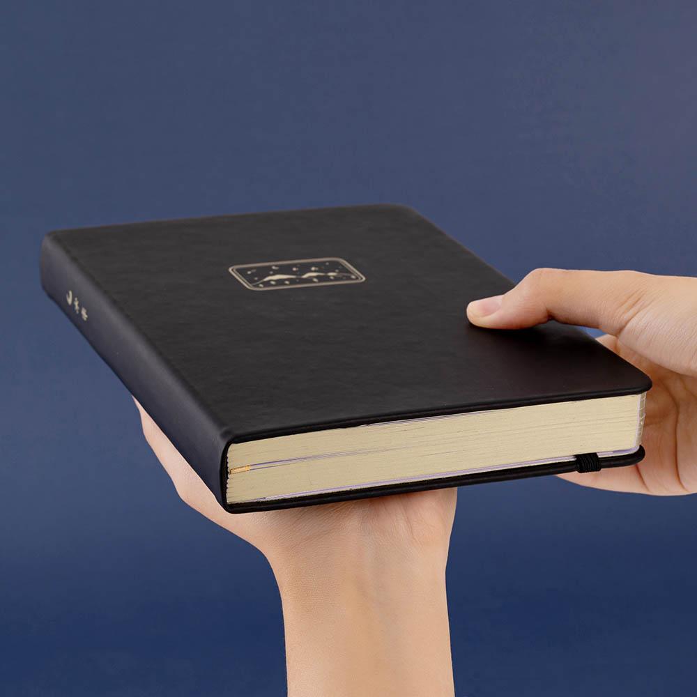 Tsuki ‘Winter Journey’ Limited Edition Bullet Journal held in hands at an angle on navy background