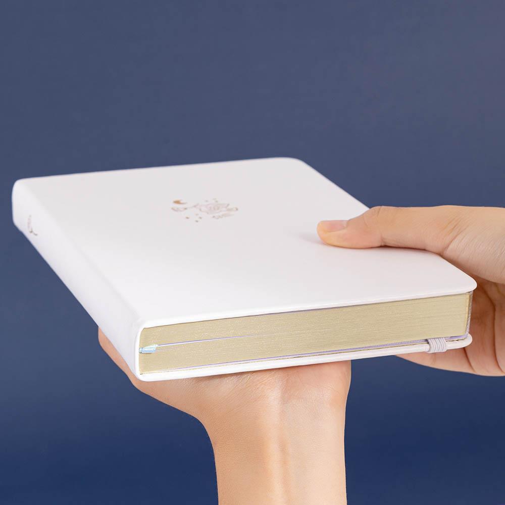 Tsuki Suzume’ Winter Limited Edition Bullet Journal held in hands at an angle on navy background