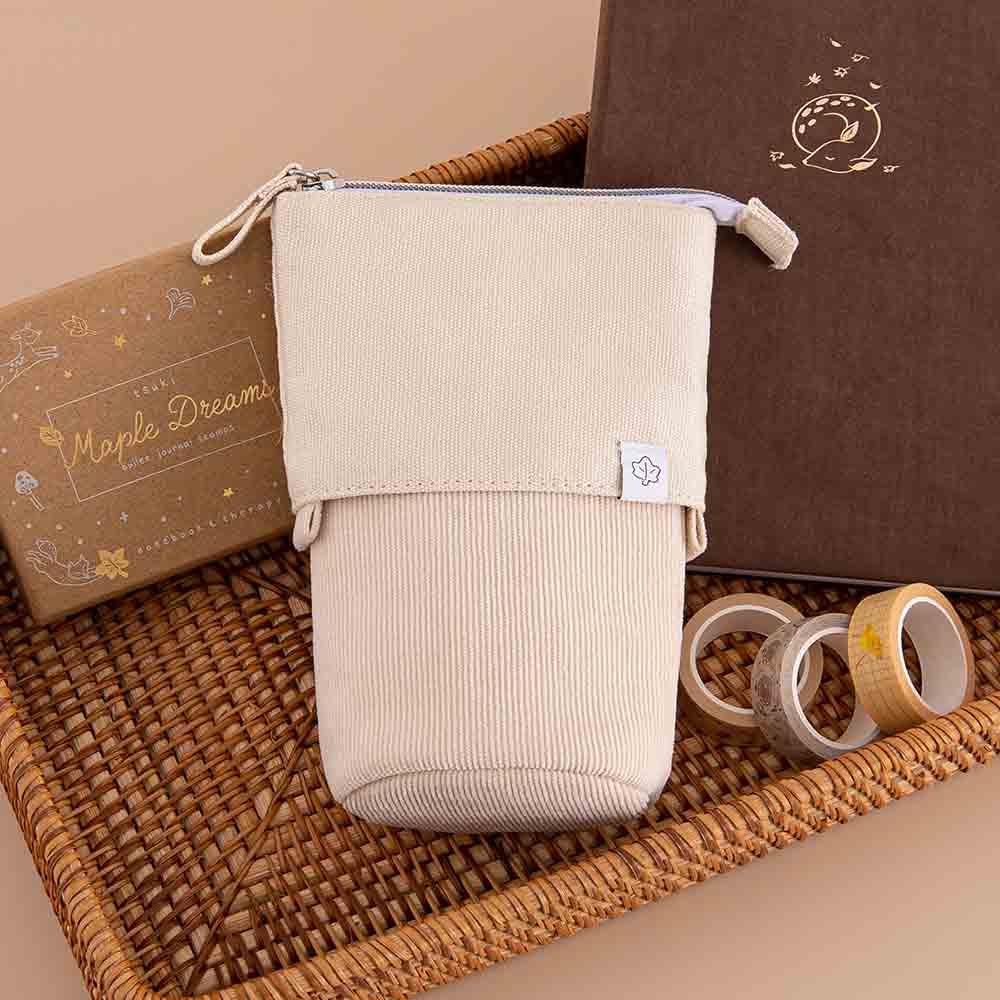 Tsuki ‘Maple Dreams’ Pop-Up Pencil case in stone with Tsuki ‘Nara’ Limited Edition Bullet Journal and Tsuki ‘Maple Dreams’ Bullet Journal Stamp Set and Tsuki ‘Maple Dreams’ Washi Tapes in brown basket on beige background
