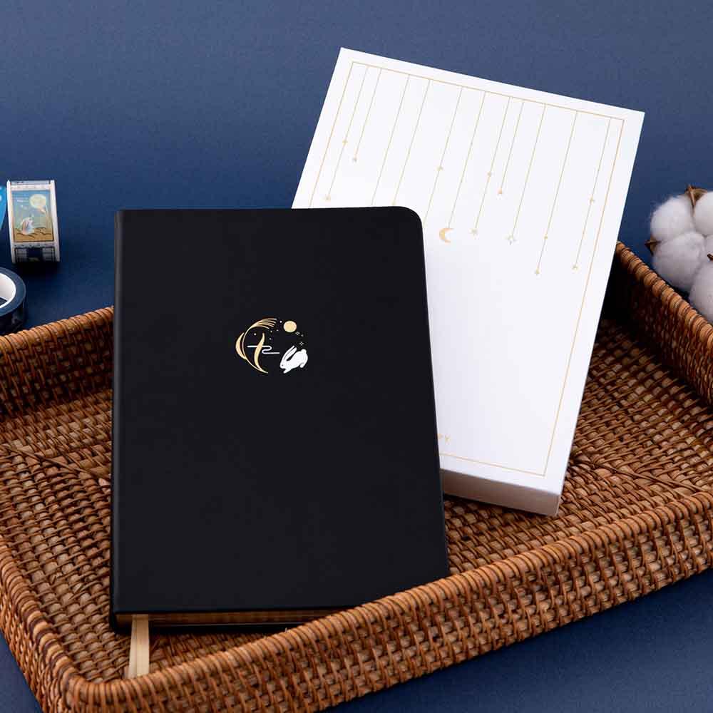 Tsuki ‘Moonlit Wish’ Limited Edition Bullet Journal with luxury gift box packaging and Tsuki ‘Moonlit Wish’ Washi Tapes with cotton flowers in brown basket on dark blue background