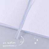 Close up of open Tsuki Four Seasons Winter Collector’s Edition Bullet Journal with two bookmark ribbons on light blue background