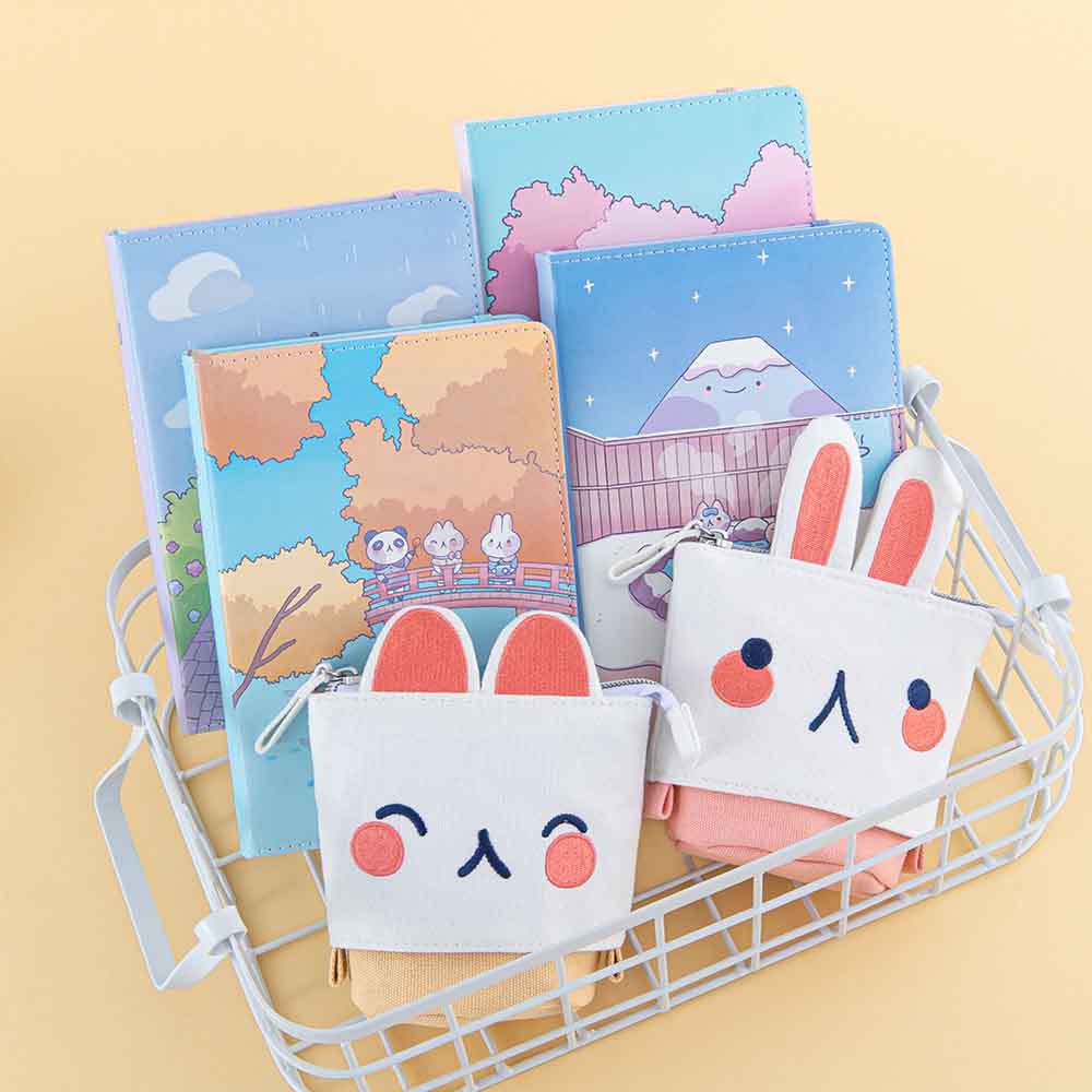 Tsuki ‘Four Seasons’ Embroidered Pop-Up Pencil Case by Notebook Therapy x Milkkoyo in kitty and bunny with Tsuki ‘Four Seasons: Autumn Edition’ Bullet Journal and Tsuki ‘Four Seasons: Winter Edition’ Bullet Journal and Tsuki ‘Four Seasons: Spring Edition’ Bullet Journal and Tsuki ‘Four Seasons: Summer Edition’ Bullet Journal in white basket on honey yellow background