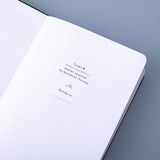 Close up of deep black Tsuki Playful Orca limited edition bullet journal on open front page on blue background