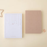Flatlay of beige constellations bullet journal with the tsuki gift box and the rose gold star paperclip