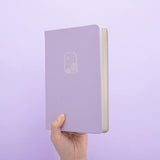Tsuki Endless Summer Limited Edition Bullet Journal in Lilac Bloom held in hands at spine angle in lilac background