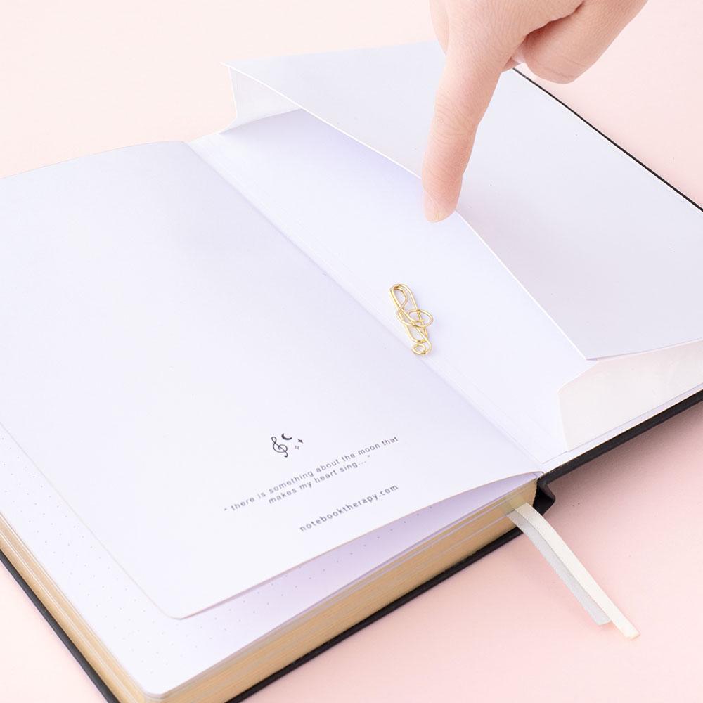 Close up of Tsuki Lunar Notes bullet journal back pocket and free gift image on pink background