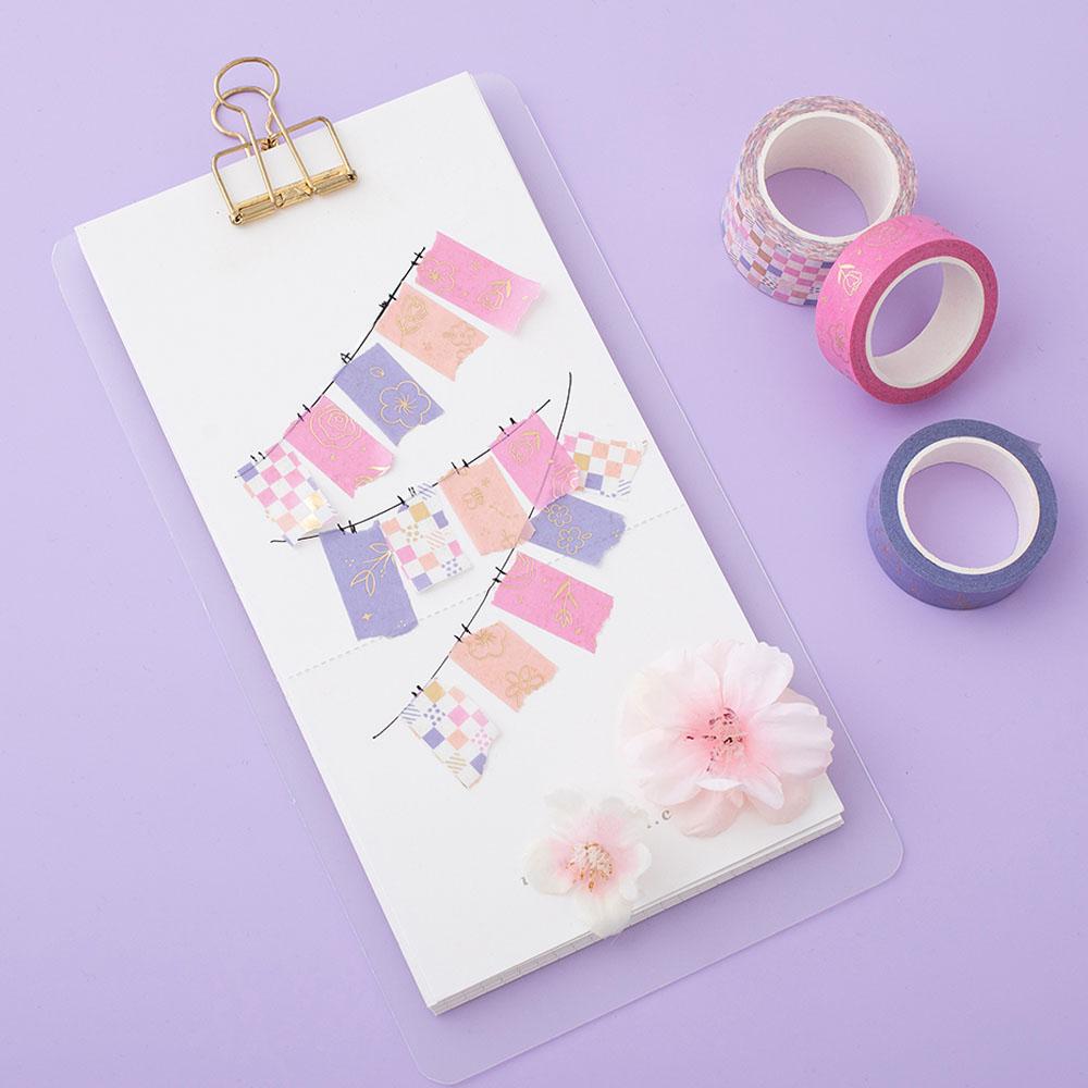 Tsuki Floral washi tapes laid out with mini banners made with washi tape on card, on lilac background