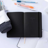 Open Tsuki Black Paper Limited Edition Hardcover Bullet Journal with Gelly Roll Pens and Tsuki Pop-Up Pencil Case in charcoal and open white page bullet journal on white background