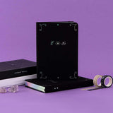 Tsuki ‘Moonlit Spell’ Limited Edition Holographic Bullet Journals in white and black paper variations with eco-friendly gift boxes with Tsuki ‘Moonlit Spell’ Washi Tapes with amethyst stones in purple background  Edit alt text