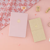 Flatlay including Sakura Breeze bullet journal and kraft paper travel notebook