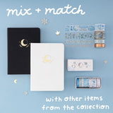 Flatlay of Tsuki Moonflower notebook in black and white and winter moonflower washi tape set with text “Mix and match with other items from collection”