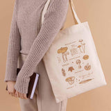 Tsuki ‘Vintage Kinoko’ Tote Bag held on model’s arm with Tsuki ‘Nara’ Limited Edition Bullet Journal in beige background