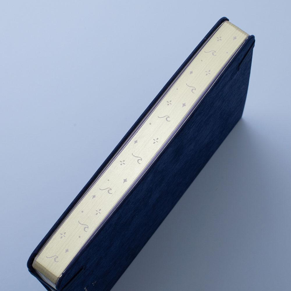 Tsuki deep blue textured vegan leather Gentle Giant luxury edition notebook at an angle with gold page edges on blue background