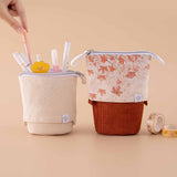 Tsuki ‘Maple Dreams’ Pop-Up Pencil cases in stone and maple with Tsuki ‘Maple Dreams’ Washi Tapes with pens held in hand in beige background