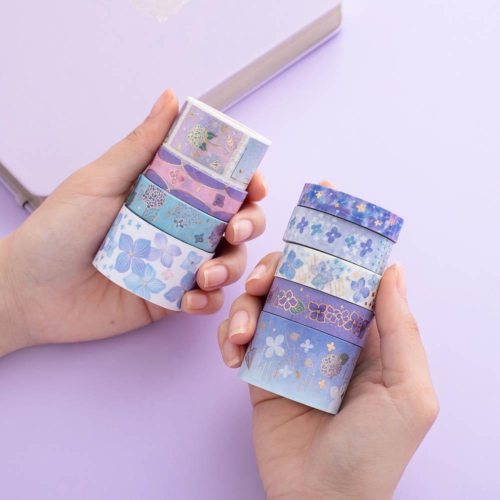 Tsuki Endless Summer Washi Tape Set with floral gold foil details held in hands with Tsuki Endless Summer Limited Edition Bullet Journal in Lilac Bloom on lilac background