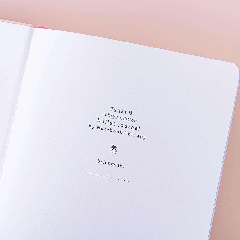Close up of the open front page of Tsuki ‘Ichigo’ Limited Edition Boba Bullet Journal on light pink background