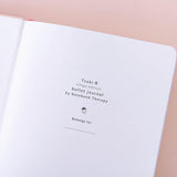 Close up of the open front page of Tsuki ‘Ichigo’ Limited Edition Boba Bullet Journal on light pink background